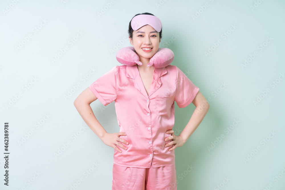 Young Asian woman wearing pajamas on green background