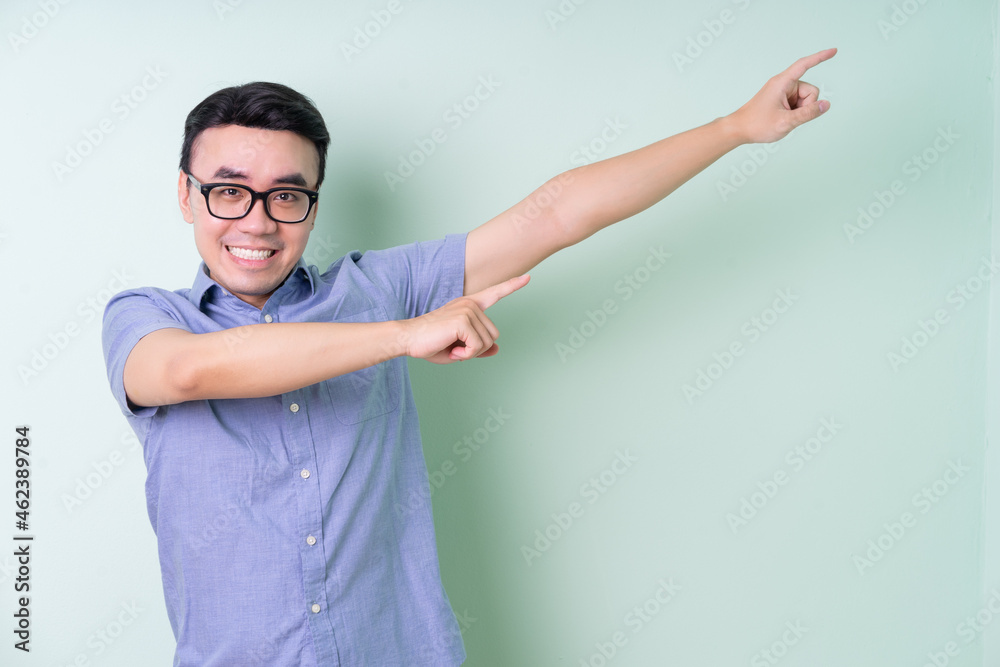 Young Asian businessman posing on green background