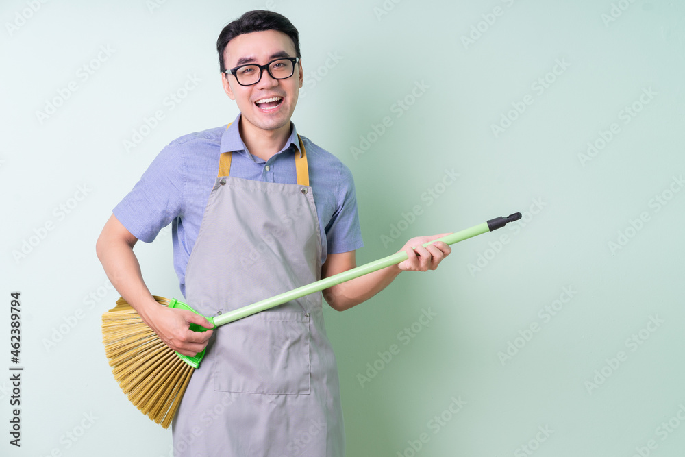 Young Asian man wearing apron posing on green background