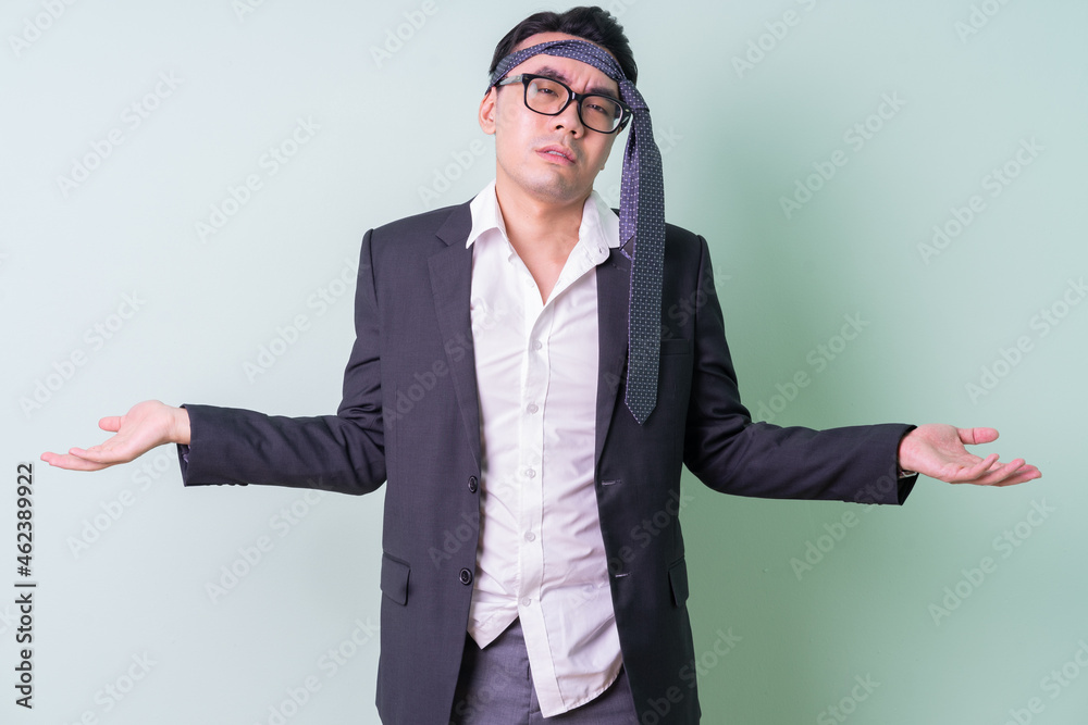 Young Asian businessman posing on green background