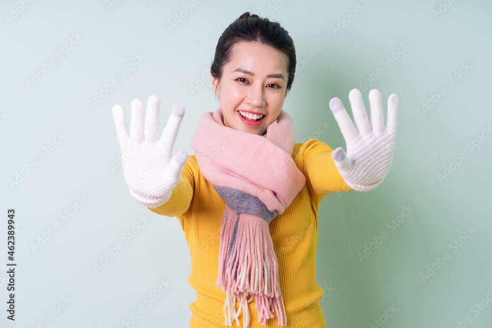 Beautiful young Asian woman wearing sweater on green background