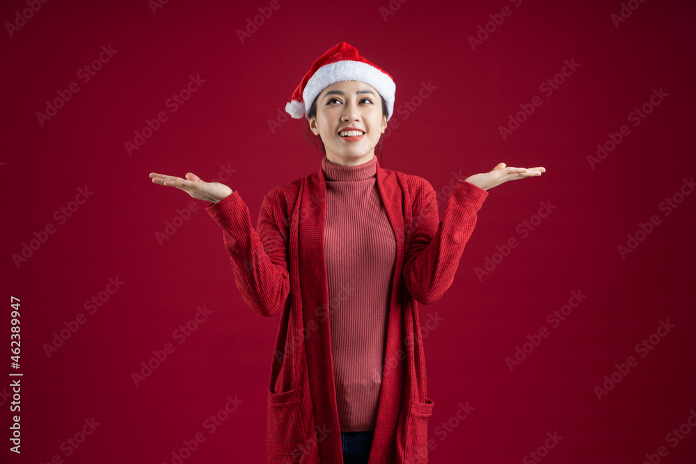 Young Asian woman wearing christmas hat on red background