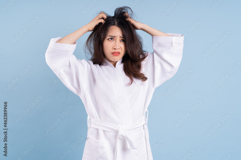 Young Asian woman wearing bathrobe on blue background