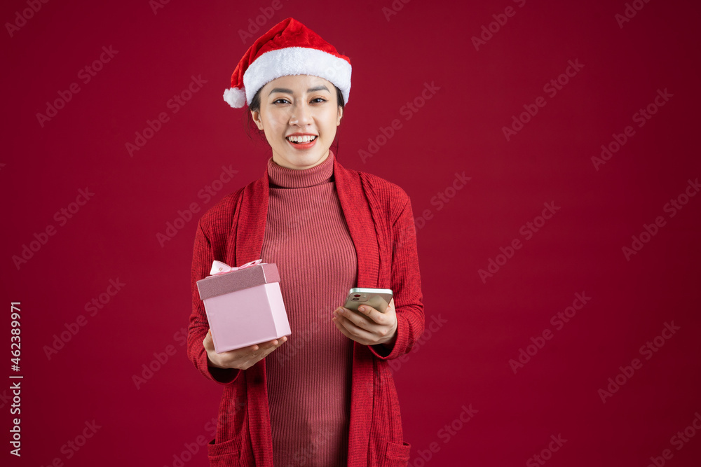 Young Asian woman wearing christmas hat on red background