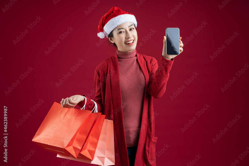 Young Asian woman wearing christmas hat on red background