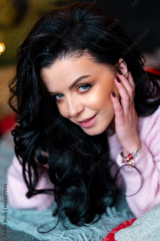 New Year photo session with festive decorations. Cheerful young woman in pink sweater posing to came