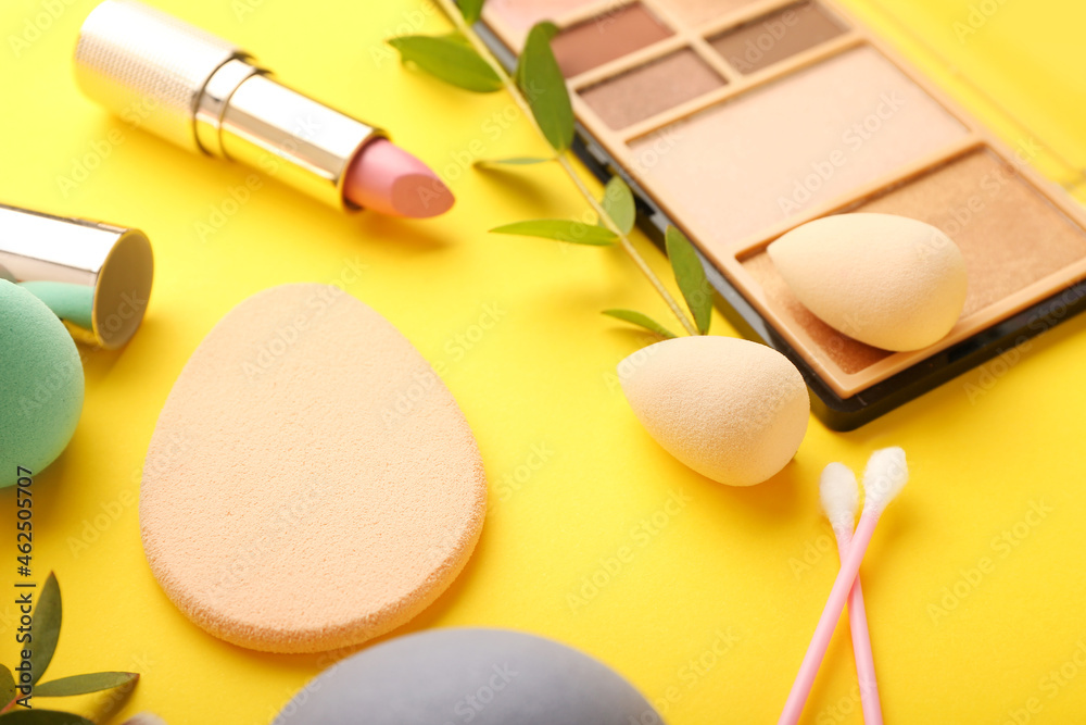 Stylish makeup sponges and decorative cosmetics on color background