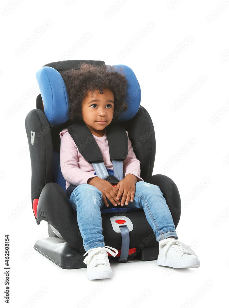 Little African-American girl buckled in car safety seat on white background