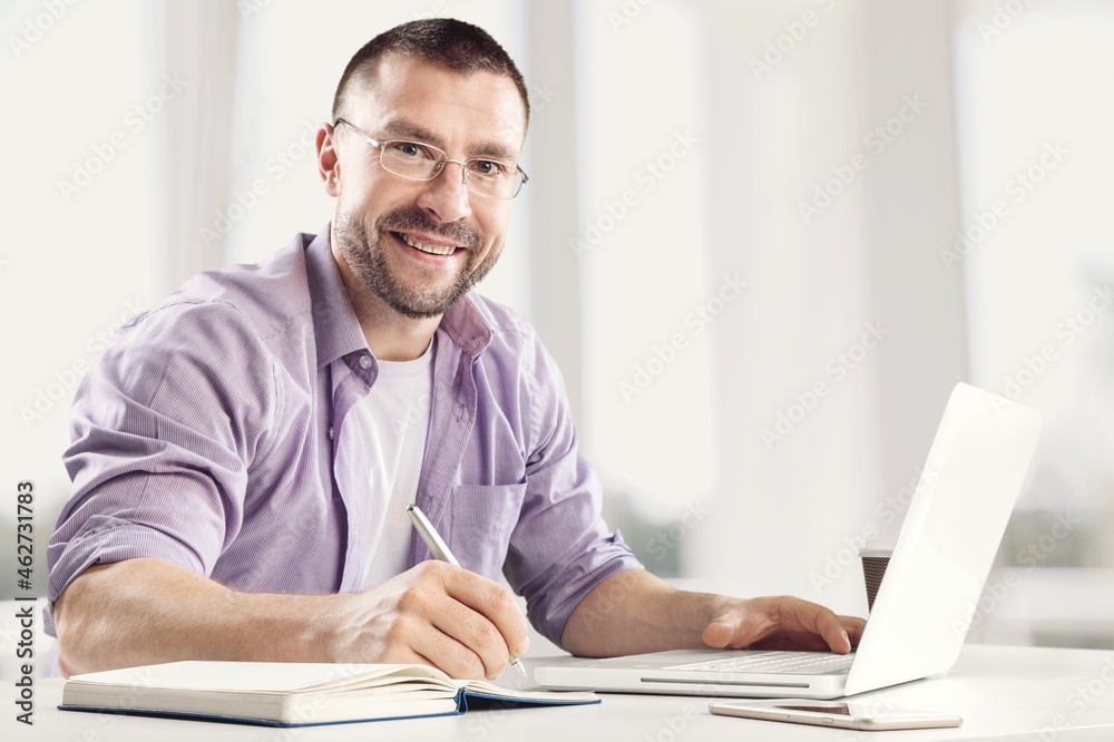 Human sitting at desk and writing down notes on a notebook