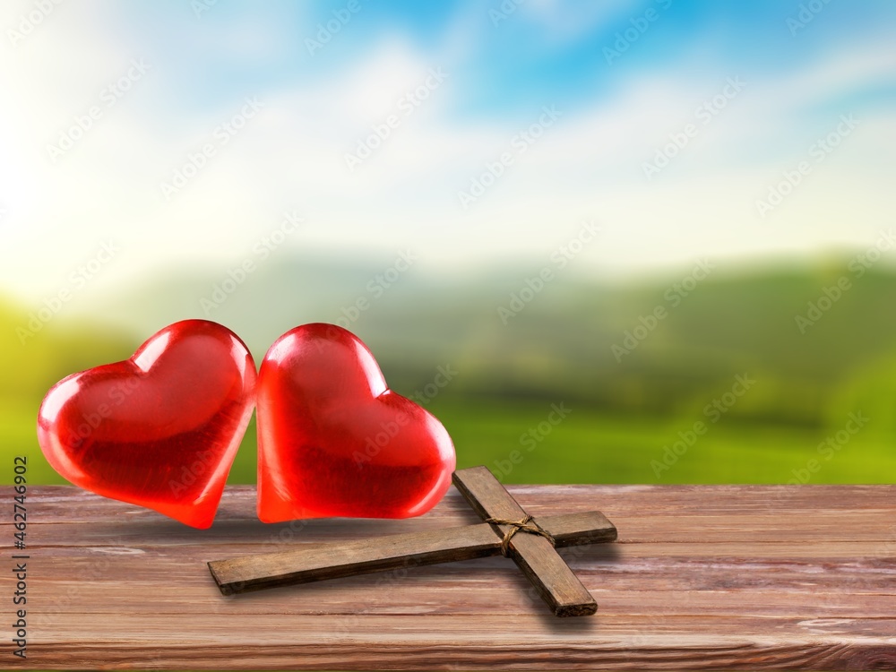 Red heart with a wooden Christian cross on floor in the morning light,