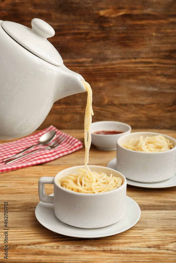 Pouring of spaghetti in cup on wooden background