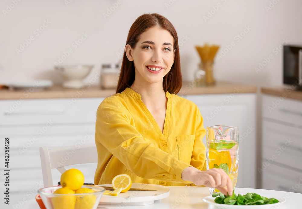 Beautiful young woman making fresh lemonade at home