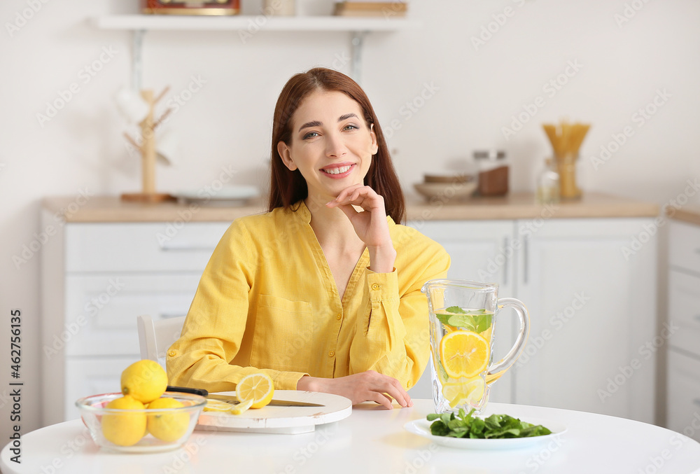 Beautiful young woman with fresh lemonade at home