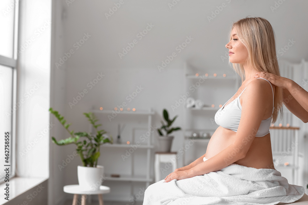 Young pregnant woman having massage in spa salon