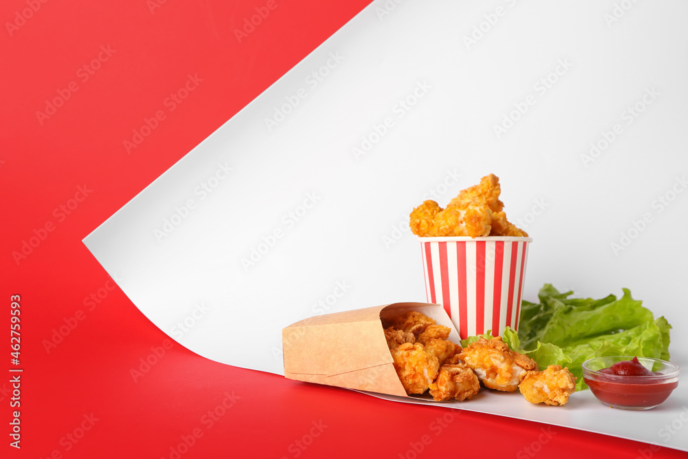 Paper boxes with tasty popcorn chicken and sauce on color background