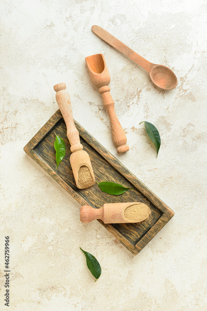 Wooden board and scoops with hojicha powder on light background