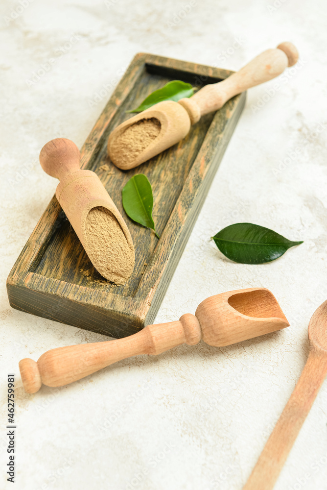 Wooden board and scoops with hojicha powder on light background