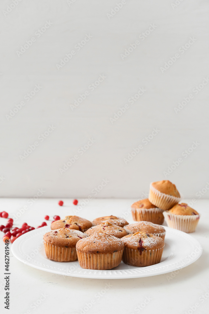 Plate with delicious cranberry muffins on white background