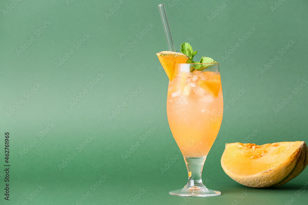 Glass with delicious melon cocktail on green background