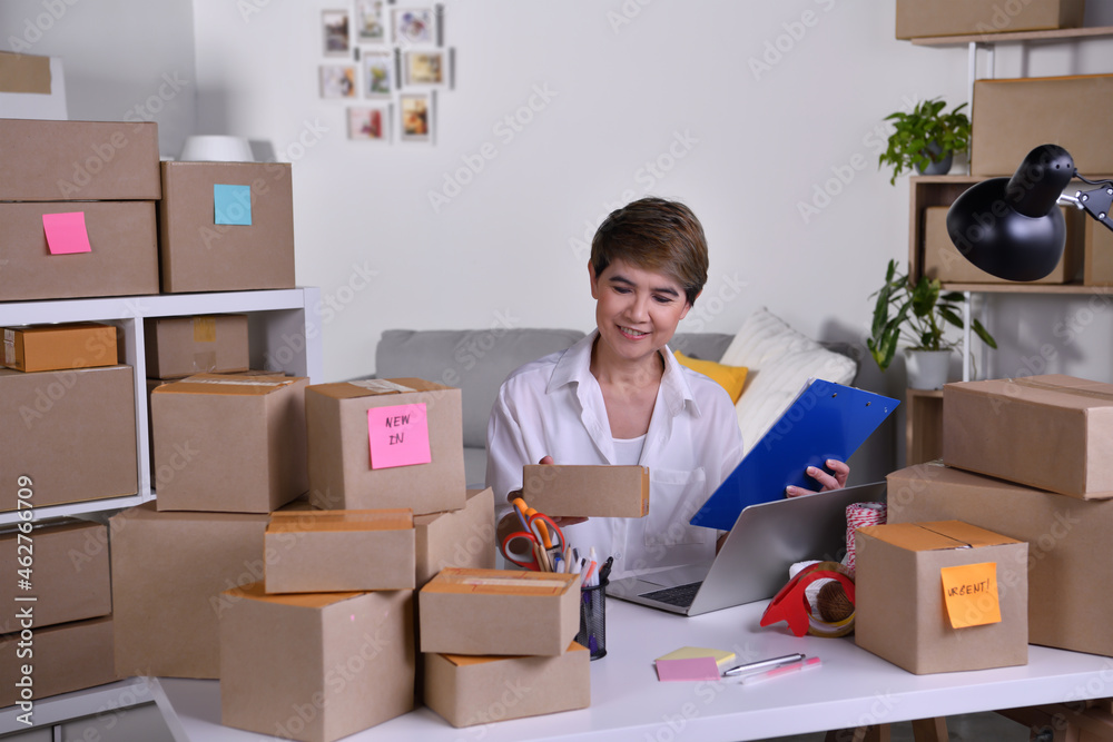 Middle aged Asian woman entrepreneur, Business owner checking address and delivery detail before shi