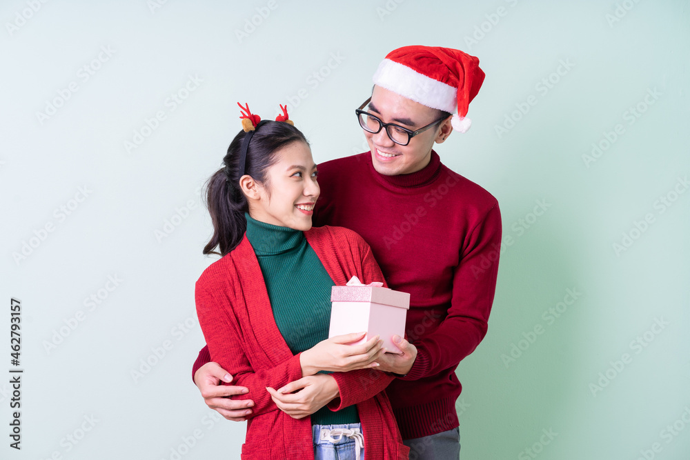 Young Asian couple posing on green background with christmas concept