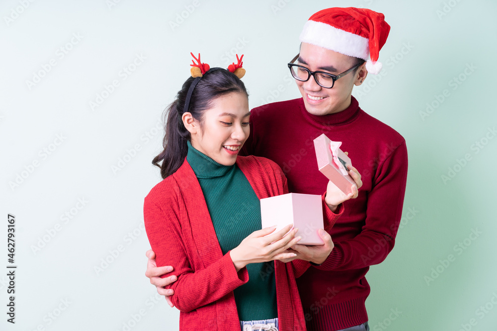 Young Asian couple posing on green background with christmas concept