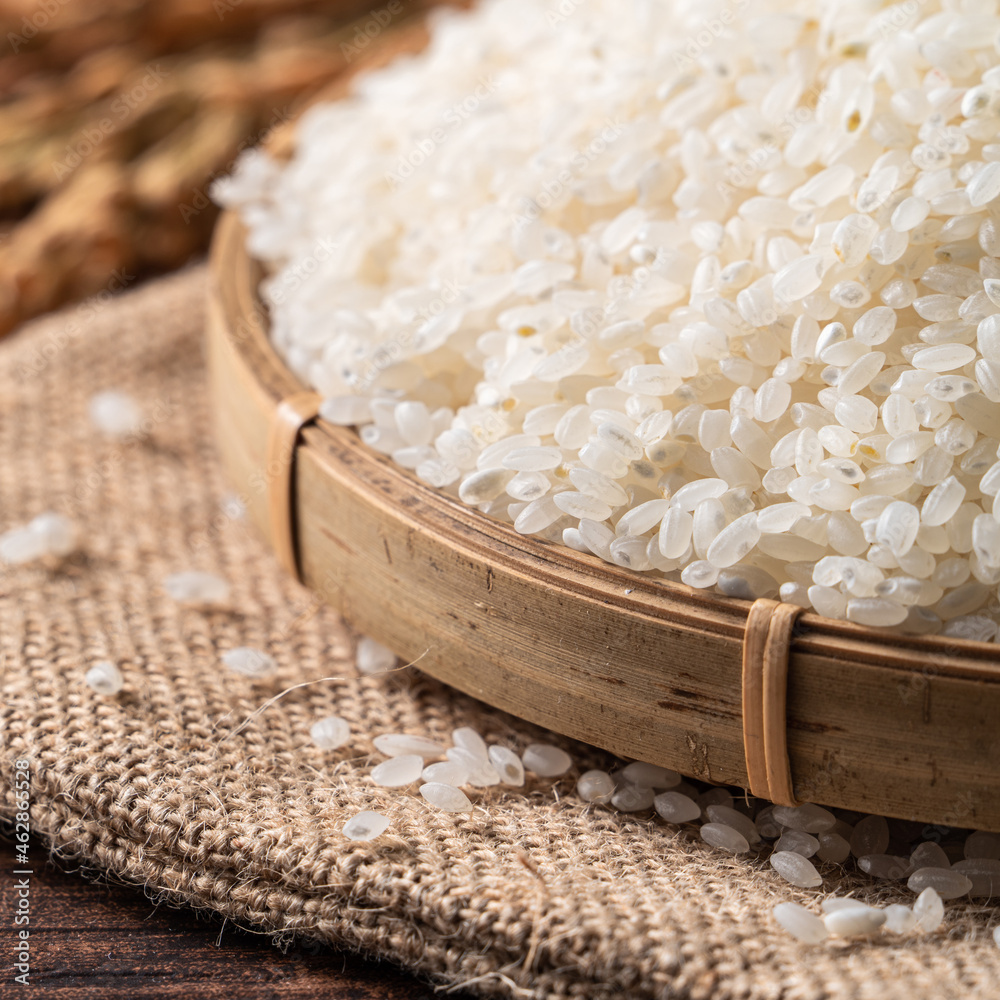 Raw white rice in a wooden bowl over table.