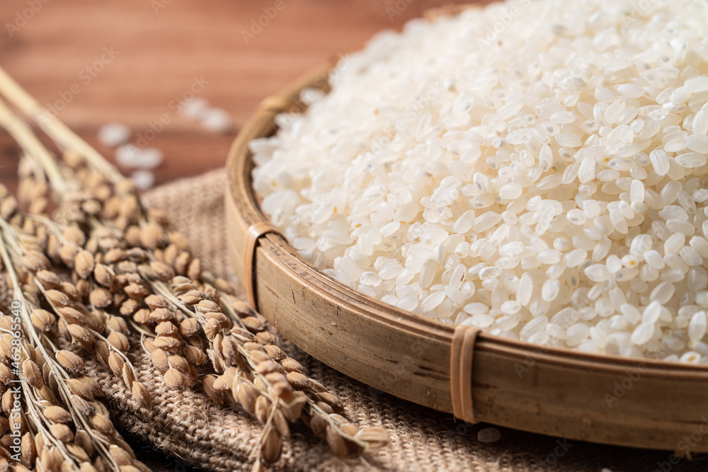 Raw white rice in a wooden bowl over table.