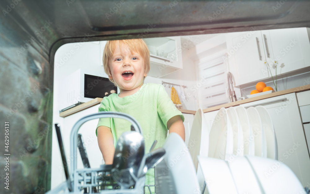 Toddler take dishes from the dishwasher at kitchen