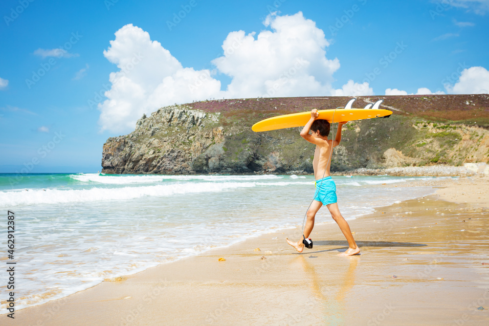 Boy run with orange surfboard walk to sea waves