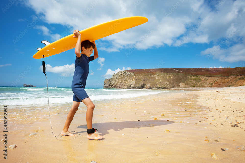 带着冲浪板的男孩从海上回到海滩