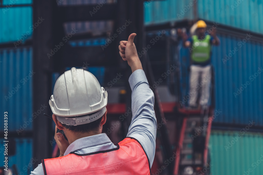 Industrial worker works with co-worker at overseas shipping container yard . Logistics supply chain 