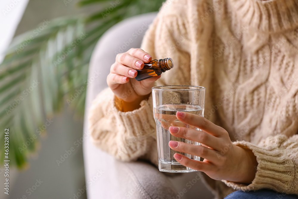 女人在家里往玻璃杯里的水里加精油