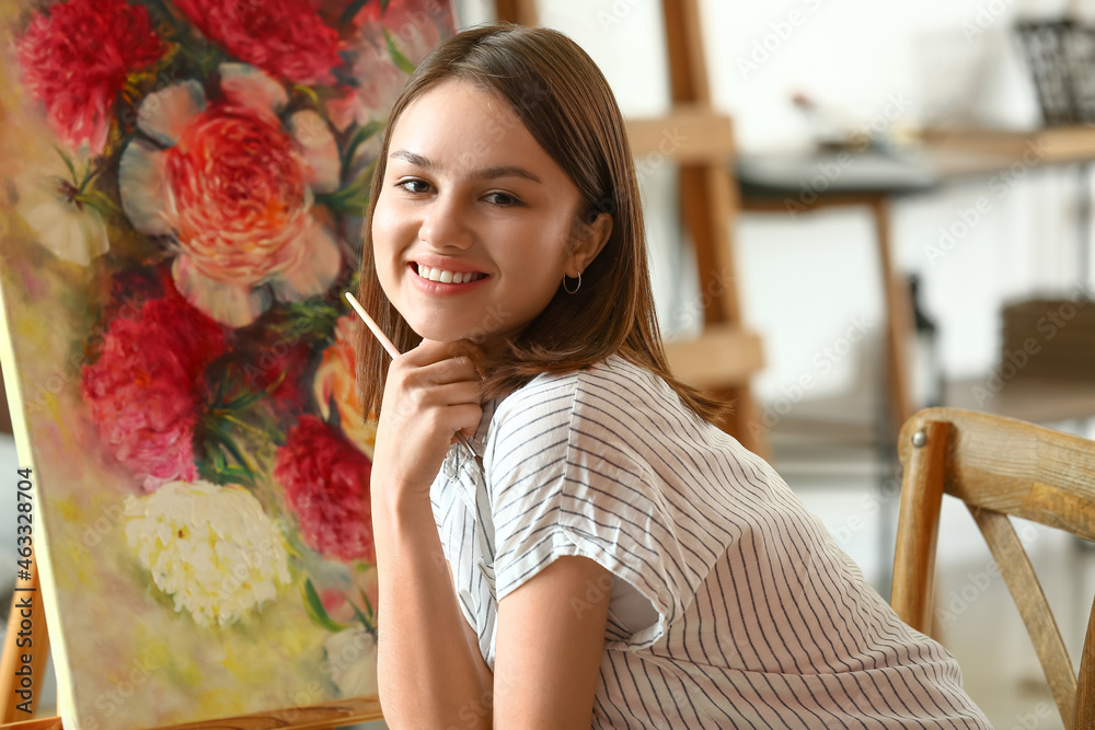 Young female artist painting in workshop