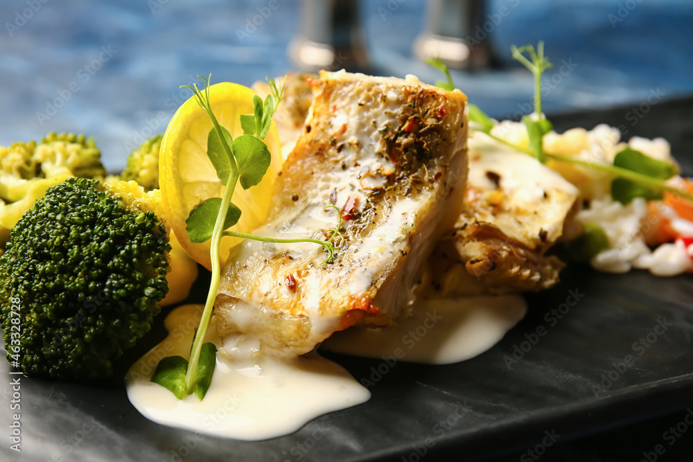 Plate with delicious baked cod fillet, rice and vegetables on color background, closeup