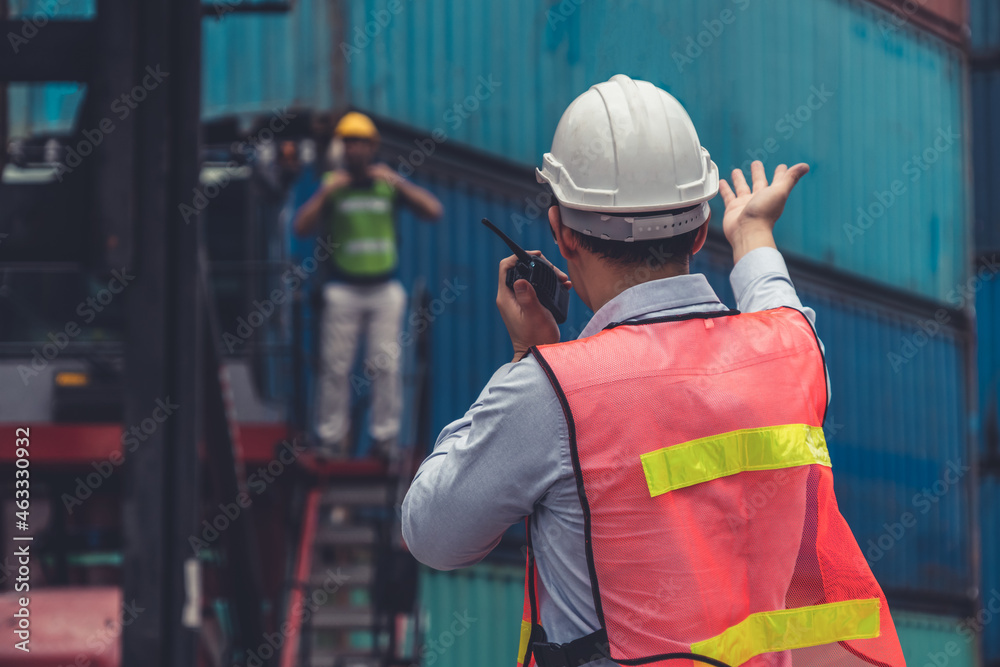 Industrial worker works with co-worker at overseas shipping container yard . Logistics supply chain 