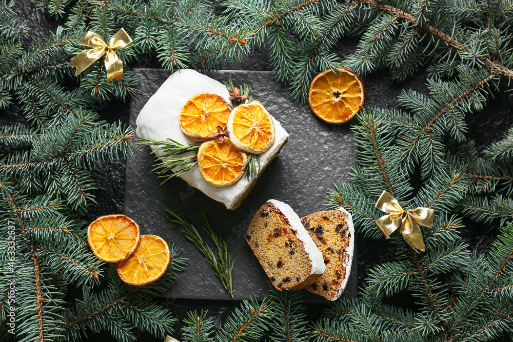 Tasty Christmas stollen with fir branches on dark background