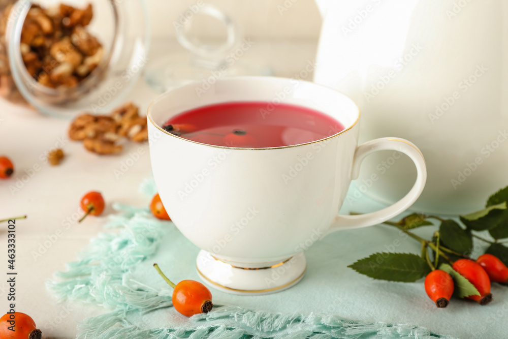 Cup of tasty rose hip tea and berries on table