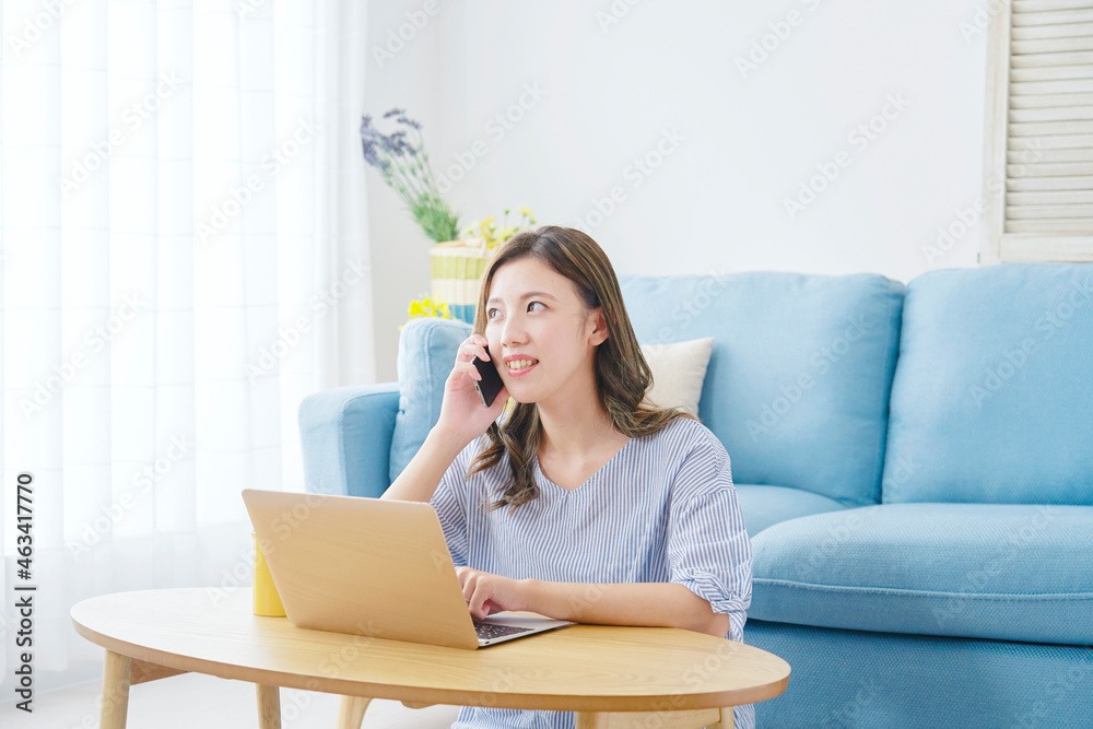 部屋でスマホで話す女性