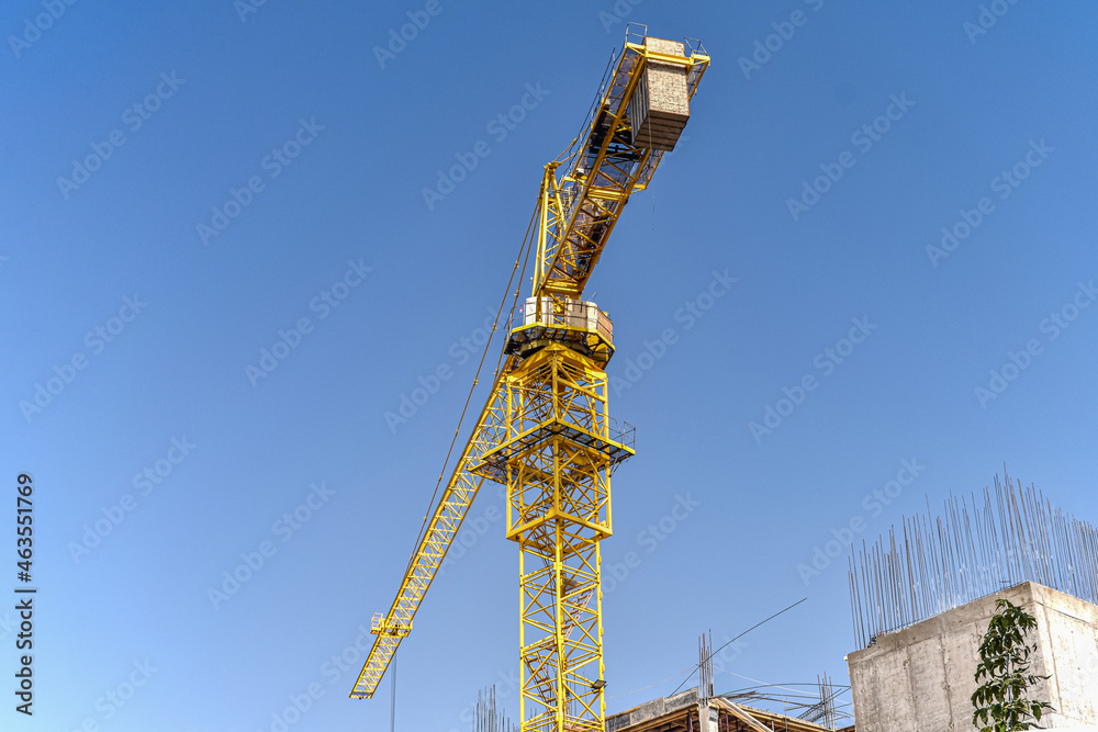 Tower crane at the construction site, against the blue sky