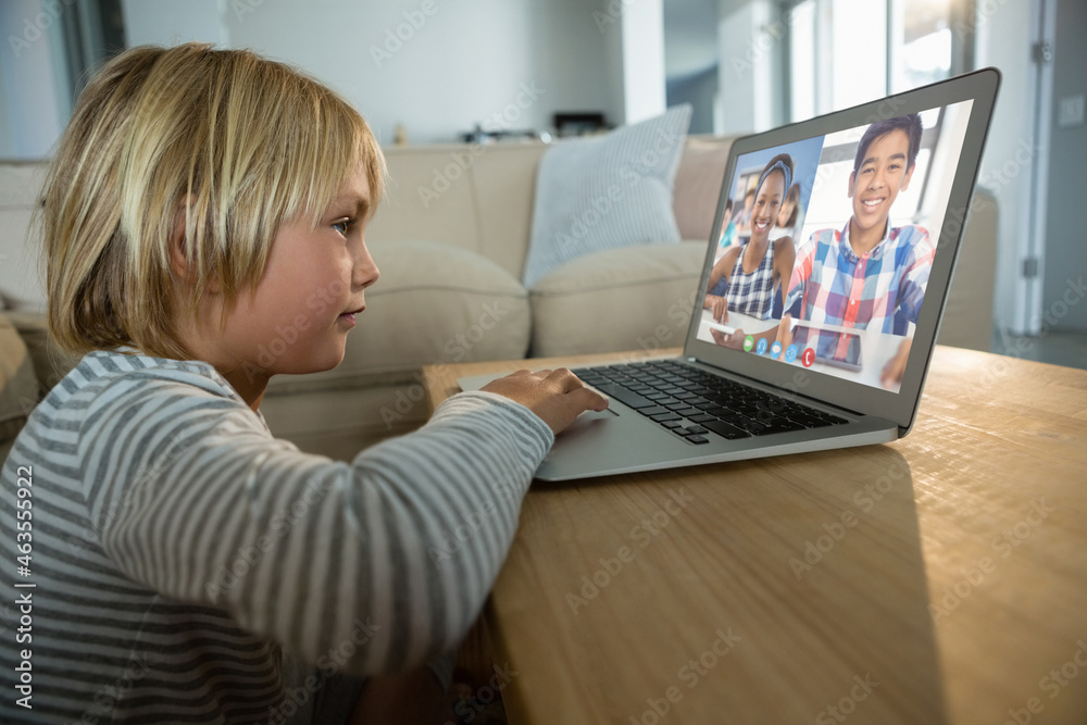 Caucasian boy using laptop for video call, with smiling diverse high school pupils on screen