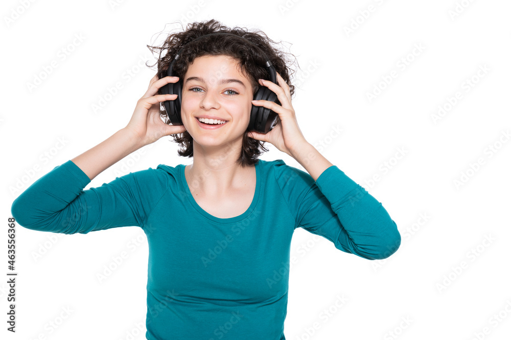 Young teenage girl wearing headphones listening and dancing to music isolated over white background.