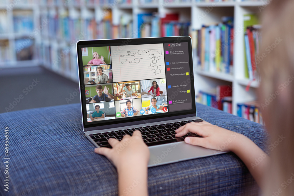 Caucasian girl using laptop for video call, with smiling diverse elementary school pupils on screen