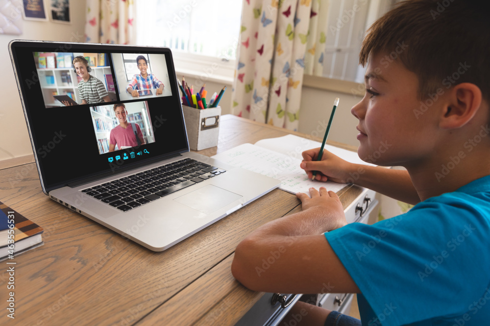 Caucasian boy using laptop for video call, with smiling diverse high school pupils on screen