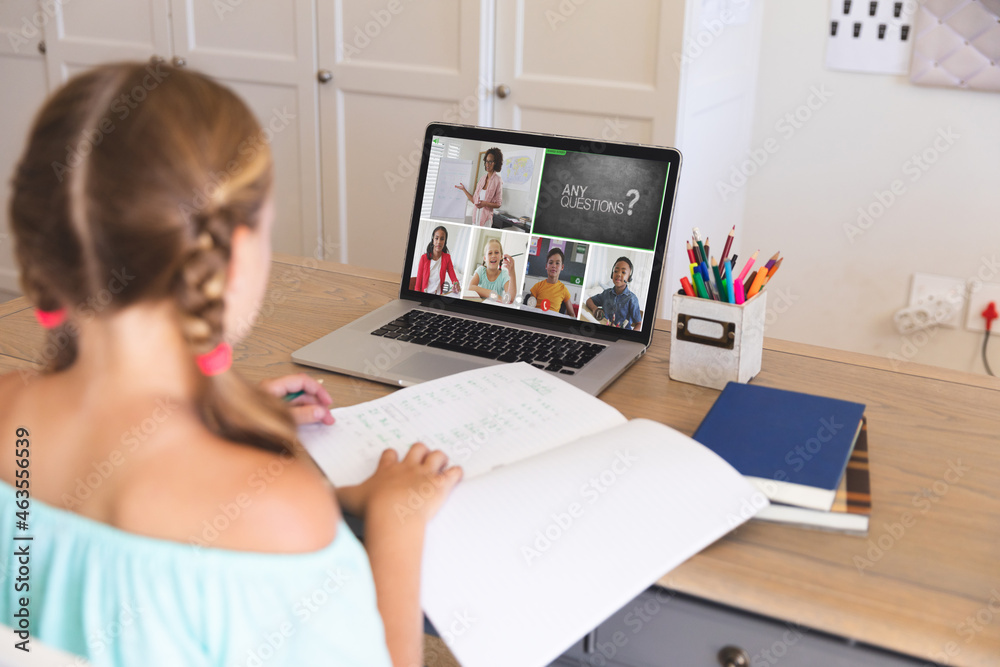 Caucasian girl using laptop for video call, with smiling diverse elementary school pupils on screen