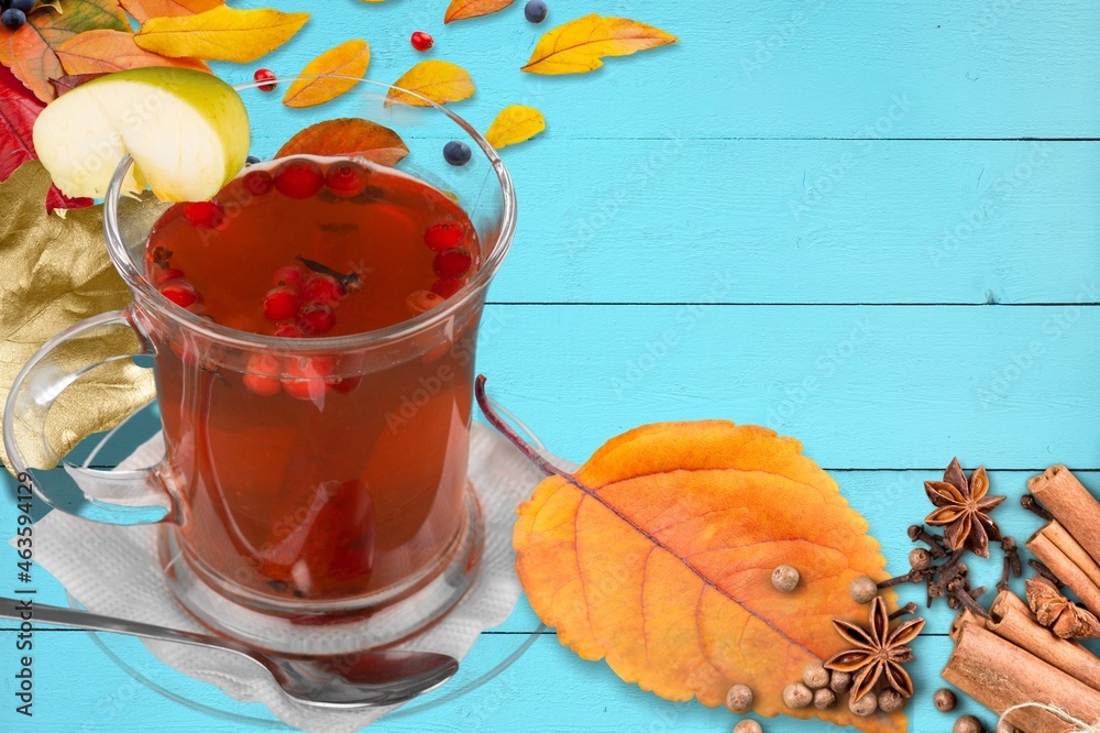 Hot tea or coffee with fall foliage, cinnamon sticks and star anise. Colorful autumn leaves