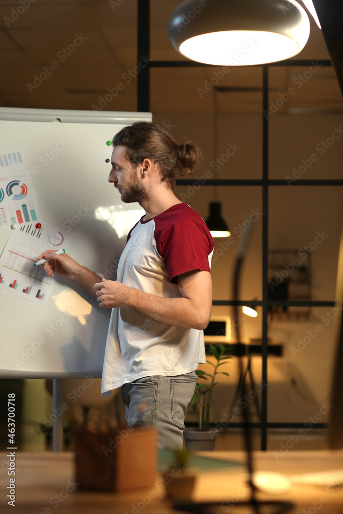 Young man giving presentation in office late in evening