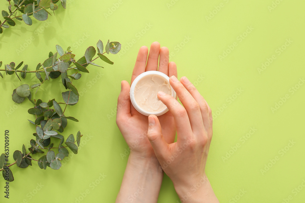 Woman applying hand cream on color background