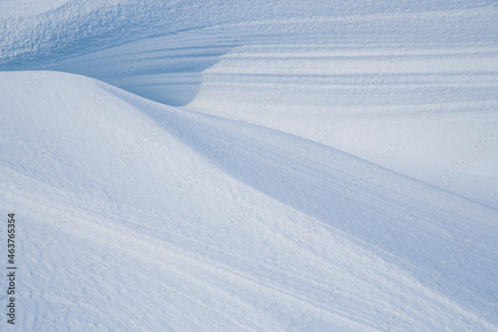 Beautiful winter background with snowy ground. Natural snow texture. Wind sculpted patterns on snow 