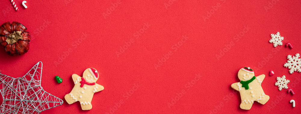 Decorated Christmas gingerbread cookies with decorations on red table background.